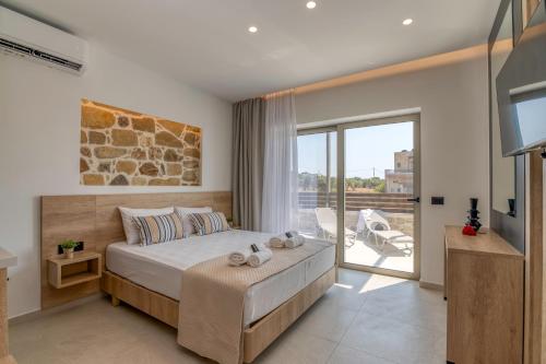 a bedroom with a bed and a tv and a balcony at Elafonisi Pearl in Elafonisi
