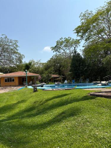 a grassy yard with a swimming pool and a house at Cabañas la Granja Rincón de Guayabitos in Rincon de Guayabitos