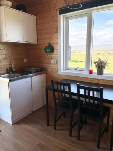 a kitchen with a table and two chairs and a window at Stormur Cottages in Vallanes