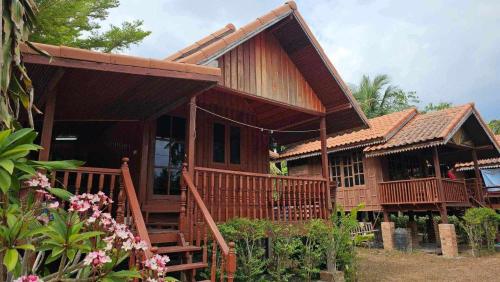 a wooden house with a porch and some flowers at Thai Home Resort in Phra Ae beach