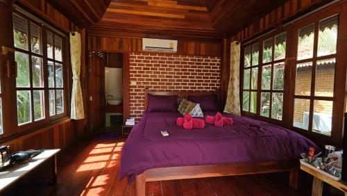 a bedroom with a purple bed with two pink stuffed animals on it at Thai Home Resort in Phra Ae beach