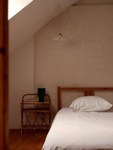 Schlafzimmer mit einem Bett mit einem weißen Kissen und einem Tisch in der Unterkunft Ferme des Millonets - petit gîte in Vienne-en-Arthies