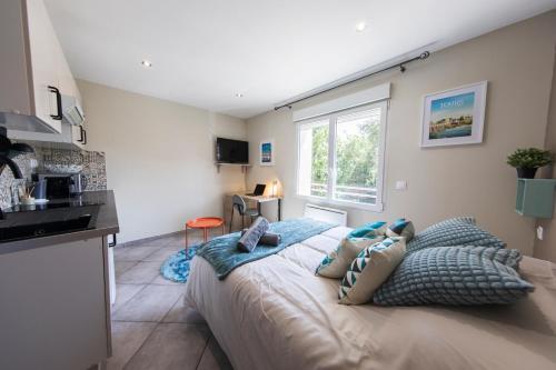 a bedroom with a bed and a kitchen with a window at Studio Cosy La Fuye, proche gare, VELORA in Tours