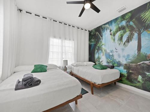 two beds in a bedroom with a tropical mural at Villa mi Amor Walkable Pool & Games in Miami