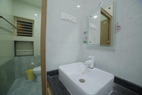a white bathroom with a sink and a toilet at Perambalur Villa in Perambalūr