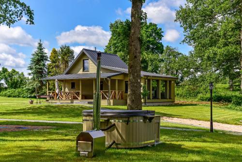 a yellow house with a tree in the yard at Vantos Lapas Rezidencija in Trakai
