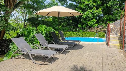 Un grupo de sillas y una sombrilla junto a una piscina. en Sunny Home Herradura - Family & Work From Beach, en Herradura