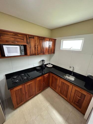 a kitchen with wooden cabinets and a black counter top at Triplex Dunas - Flecheiras in Trairi