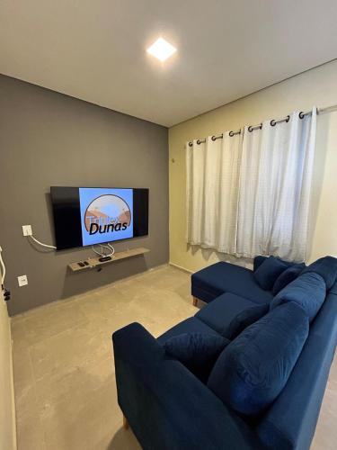 a living room with a blue couch and a flat screen tv at Triplex Dunas - Flecheiras in Trairi