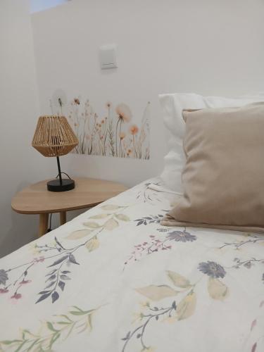 a bed with a floral bedspread and a table with a lamp at Casa do Hilário in Viseu