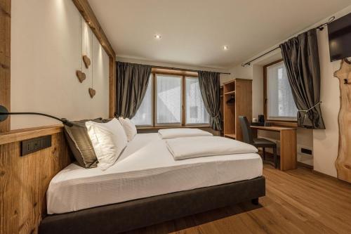 a bedroom with a large bed with a desk and window at Le Crode Bed and Breakfast in Auronzo di Cadore