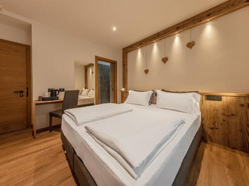 a large white bed in a room with a desk at Le Crode Bed and Breakfast in Auronzo di Cadore