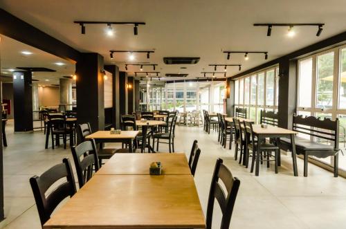 Un restaurante con mesas y sillas de madera y ventanas. en Ibis Joao Pessoa Praia, en João Pessoa