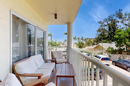 een veranda met een bank en een tafel op een balkon bij Sunset Vistas Condo 203S in St Pete Beach