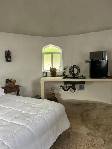 a bedroom with a bed and a window and a television at El bungalito de chuburna in Mérida
