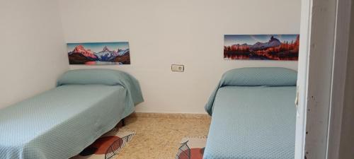2 Einzelbetten in einem Zimmer mit 2 Gemälden an der Wand in der Unterkunft La posada del Mozarabe in Alquife