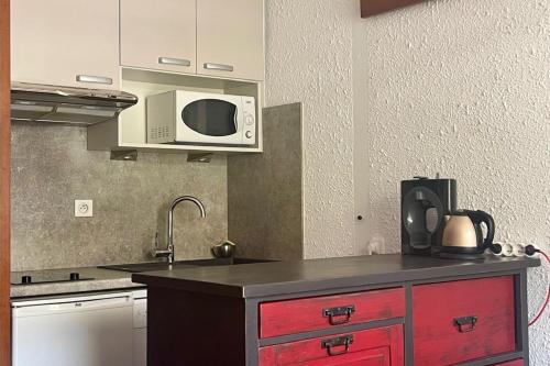 - une cuisine avec une armoire rouge et un four micro-ondes dans l'établissement Cosy T2 with sunny terrace in Saint-Chaffrey, à Saint-Chaffrey