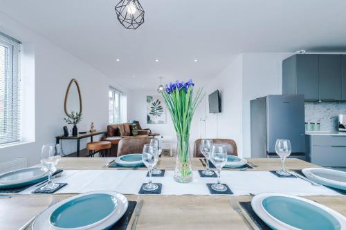 a dining room table with plates and wine glasses at The Hansas Residences - Two Elegant & Spacious Townhouses - Perfect for Business or Work Stays by Parydise Properties in Harlescott