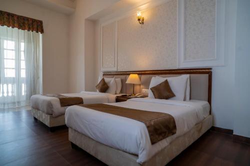 a hotel room with two beds and a window at Hotel Merwara Estate- A Luxury Heritage Resort in Ajmer