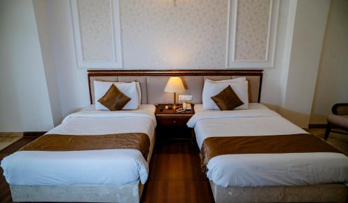 a hotel room with two beds and a table with a lamp at Hotel Merwara Estate- A Luxury Heritage Resort in Ajmer