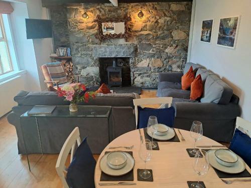 a living room with a table and a stone fireplace at Hollybank, Kyleakin in Kyleakin