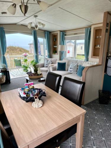 a dining table with chairs and a living room at Celebration by the sea in Redcar
