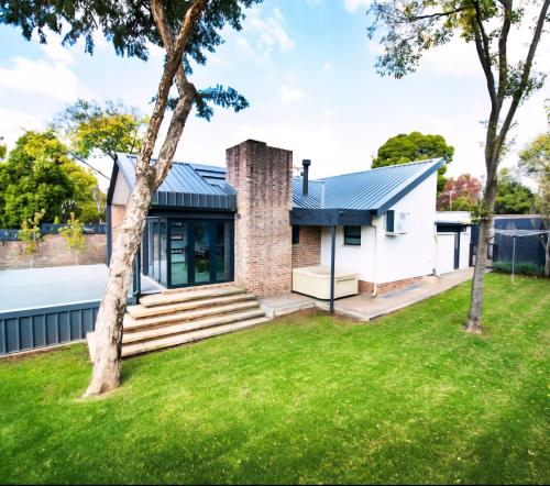une maison avec une cheminée en briques et de l'herbe verte dans l'établissement Rusgerus, à Pretoria