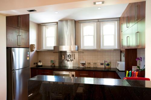 a kitchen with wooden cabinets and a stainless steel refrigerator at Lowena Cafe and Accommodation in Hobart