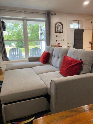 a gray couch with red pillows in a living room at Our Place Up North BnB in Huntsville