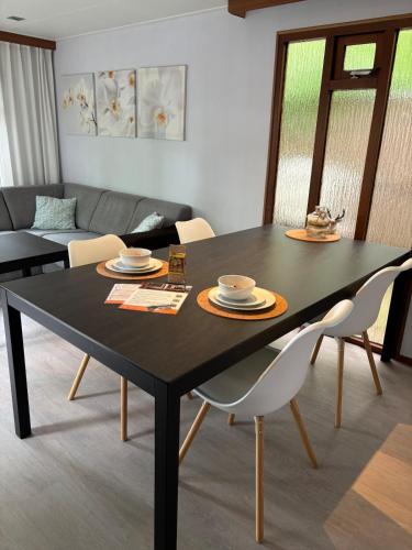 a dining room with a black table and chairs at Heerlijk chalet midden op de Veluwe in Hoenderloo in Hoenderloo