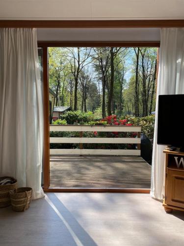 a room with a sliding glass door to a garden at Heerlijk chalet midden op de Veluwe in Hoenderloo in Hoenderloo