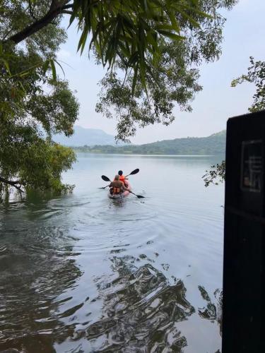 a person in a kayak on a body of water at Kamshet Lakeside Serene Artist Villa in Somavadi