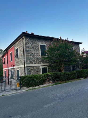 a stone building with a tree in front of a street at Il marchese Malaspina con idromassaggio in Mulazzo