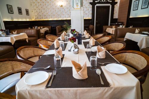 a dining room with a long table with white plates at Hotel Merwara Estate- A Luxury Heritage Resort in Ajmer