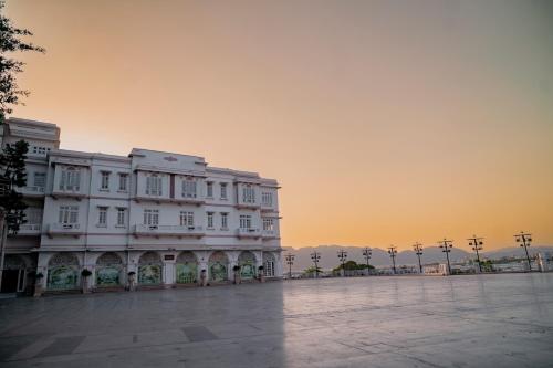 a large white building with a sunset in the background at Hotel Merwara Estate- A Luxury Heritage Resort in Ajmer