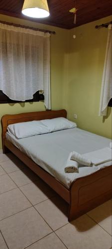 a bedroom with a large bed with white sheets and a window at Erifily's House in Nea Kalikratia