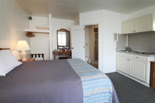 a bedroom with a large bed and a kitchen at Lark Motel in Stone Harbor