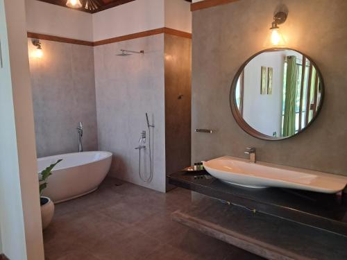 Un baño con bañera, lavabo y espejo. en River Shades Hotel, en Hikkaduwa