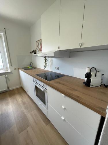 a kitchen with white cabinets and a wooden counter top at ZORO - 4 Zimmer- Küche - Balkon in Memmingerberg