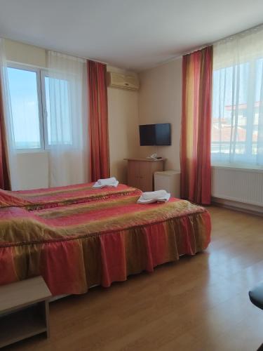 a bedroom with a large bed with red curtains at Къща за гости ГАЛАНТ in Byala