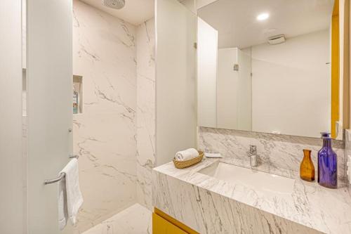 Un baño blanco con lavabo y espejo. en Rooftop pool- family apartment- ocean view -close, en Cancún