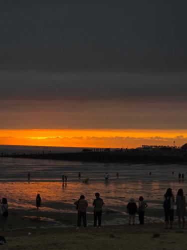a group of people standing on the beach at sunset at 경주펜션 Gyeongju Pension in Incheon