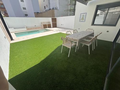 eine Terrasse mit grünem Gras sowie einem Tisch und Stühlen in der Unterkunft Casa con PISCINA y CINE in Paterna
