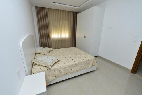 a bedroom with a bed in a white room at Dar Hella Apartments in El Maamoura