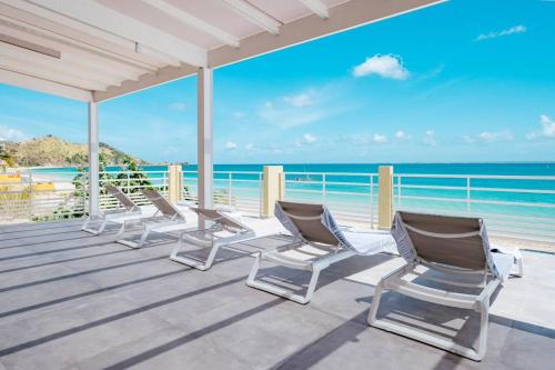 a row of chairs on a deck overlooking the ocean at Suite 7 Mogador Residence, 1BR, brand-new, rare & luxury, beachfront in Grand Case