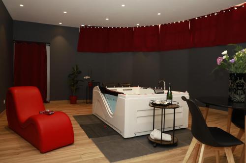 a bathroom with a bath tub and a red chair at La Suite Romantique in Rethel