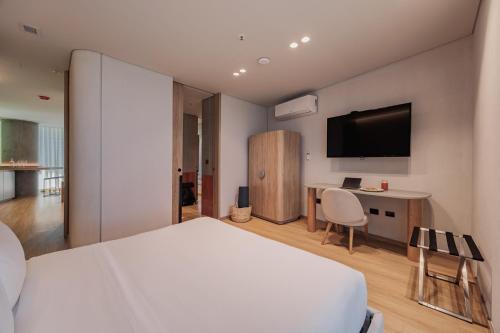 a bedroom with a bed and a desk and a tv at Seissta Medellín in Medellín