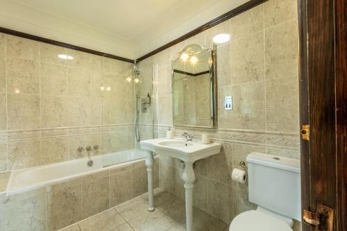 a bathroom with a sink and a tub and a toilet at The Tudor Mansion in Bournemouth