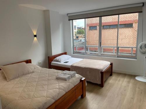 a bedroom with two beds and a large window at Aparta hotel Montecristo Suites in Quimbaya