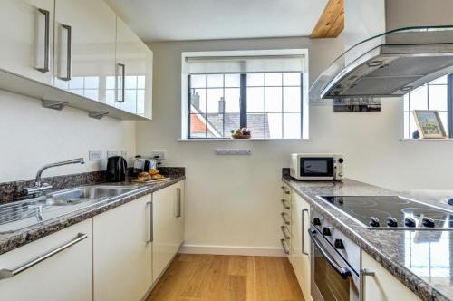 a kitchen with white cabinets and a sink at Flat 8 Broadleys in Swanage